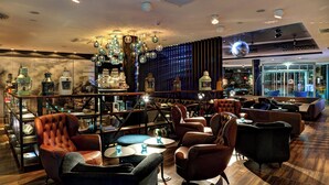 Ein stilvoller Lounge-Bereich mit Ledersesseln, runden Tischen und dekorativer Beleuchtung.