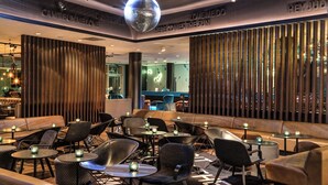 Ein stilvoller Lounge-Bereich mit Ledersofas, runden Tischen und stimmungsvoller Beleuchtung.