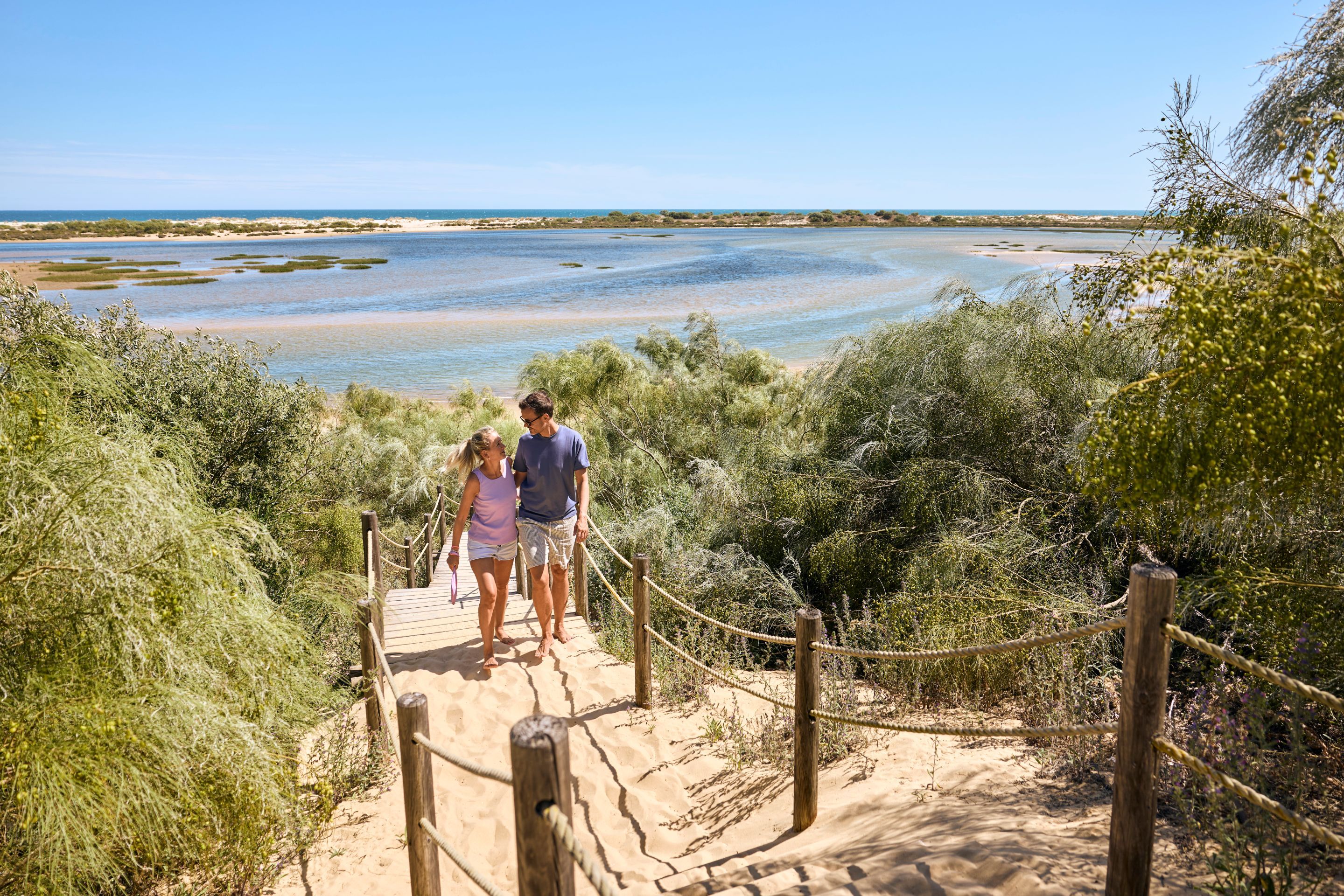 A wooden boardwalk leading to a beach with clear skies.