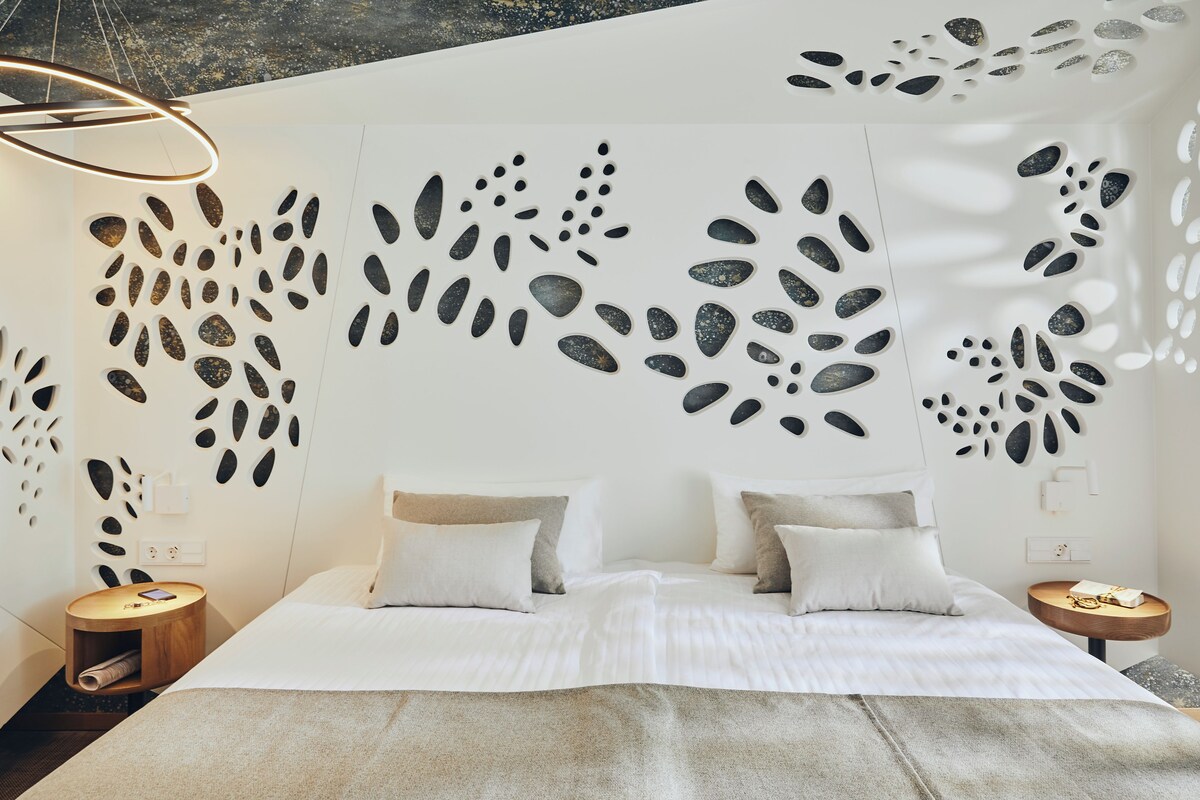 A modern bedroom with a large bed, two bedside tables, and a unique wall design.