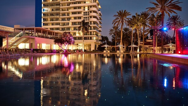 A hotel with a pool, palm trees, and a modern building with balconies. - ROBINSON JANDIA PLAYA - Adults only (Pajara)