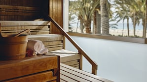 Una panchina di legno con un asciugamano e un secchio di legno, con vista su una spiaggia con palme.