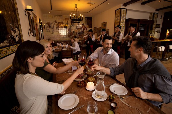 A group of people dining at a restaurant with a large, ornate mirror and a chandelier.