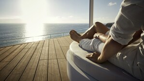 A person sitting on a cushioned bench with a view of the ocean. - ROBINSON JANDIA PLAYA - Adults only (Pajara)