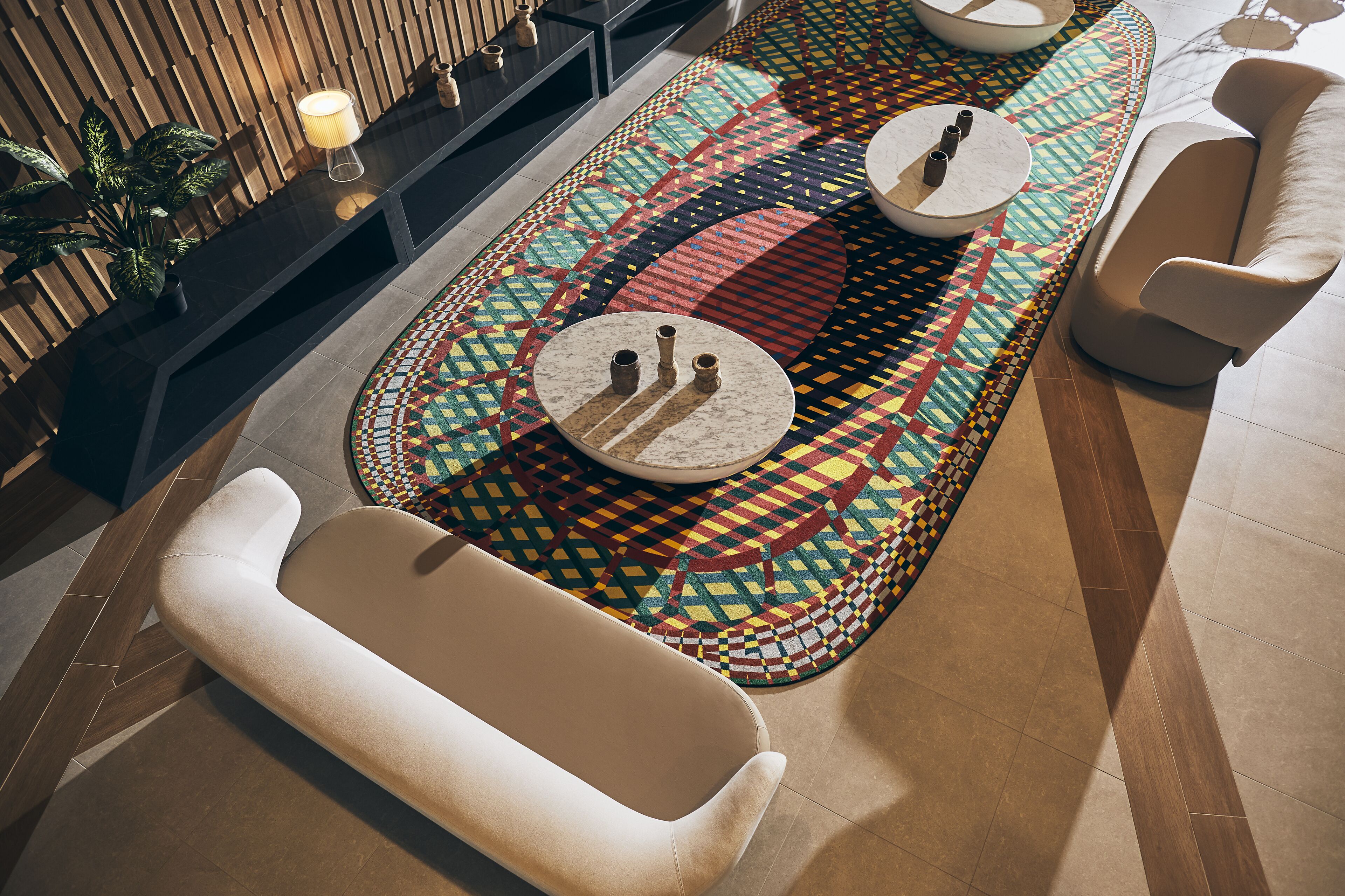 A modern lounge area with a patterned rug, a seating bench, and a side table with a lamp.