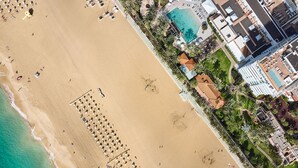 An aerial view of a beach with rows of sun loungers and a swimming pool adjacent to a resort area. - ROBINSON JANDIA PLAYA - Adults only (Pajara)