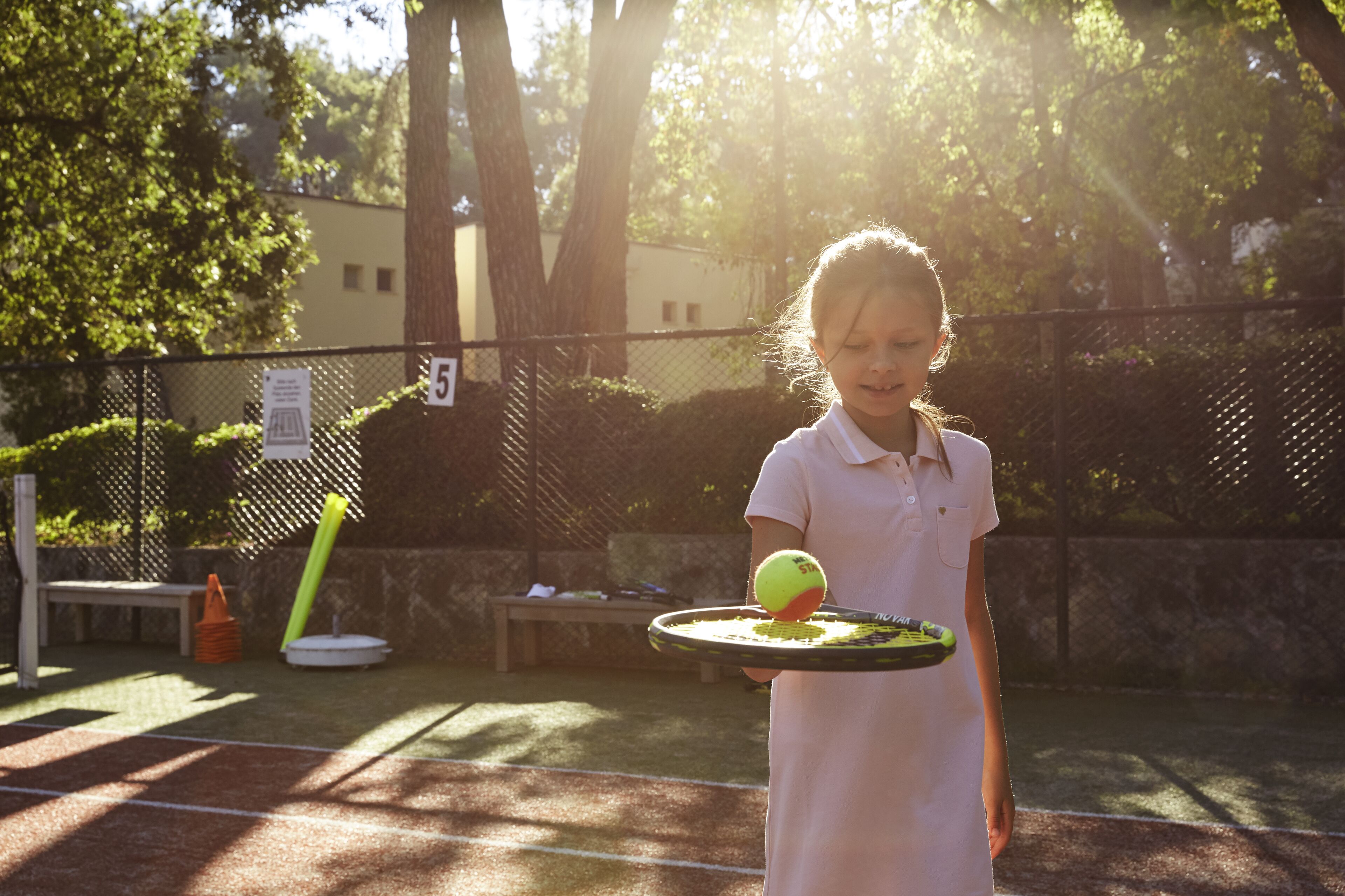 A tennis court with a net, a bench, and a fence.