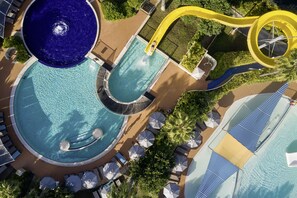 A large outdoor swimming pool with a water slide, surrounded by lounge chairs and umbrellas. - ROBINSON PAMFILYA - All Inclusive (Manavgat)