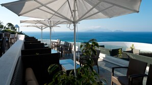 A terrace with outdoor seating, umbrellas, and a view of the ocean. - ROBINSON DAIDALOS (Kos)