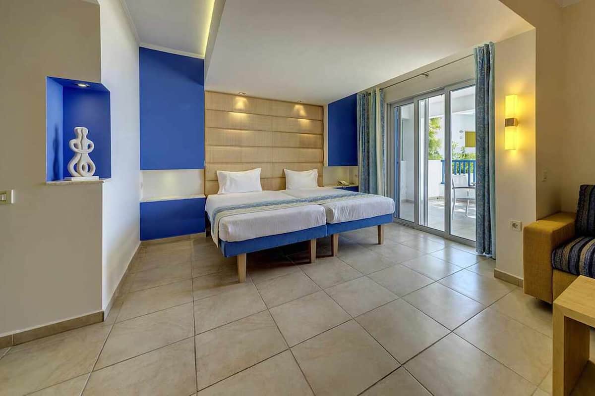 A modern hotel room with a large bed, a sofa, and a balcony with a view.