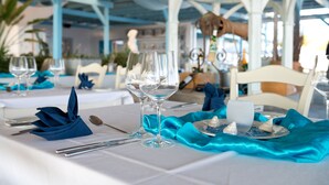 A table set with blue napkins, wine glasses, and a dessert plate with a blue and white design. - ROBINSON DAIDALOS (Kos)