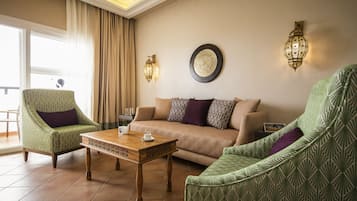 Una sala de estar con un sofá, dos sillones, una mesa de centro de madera y dos lámparas de pared.