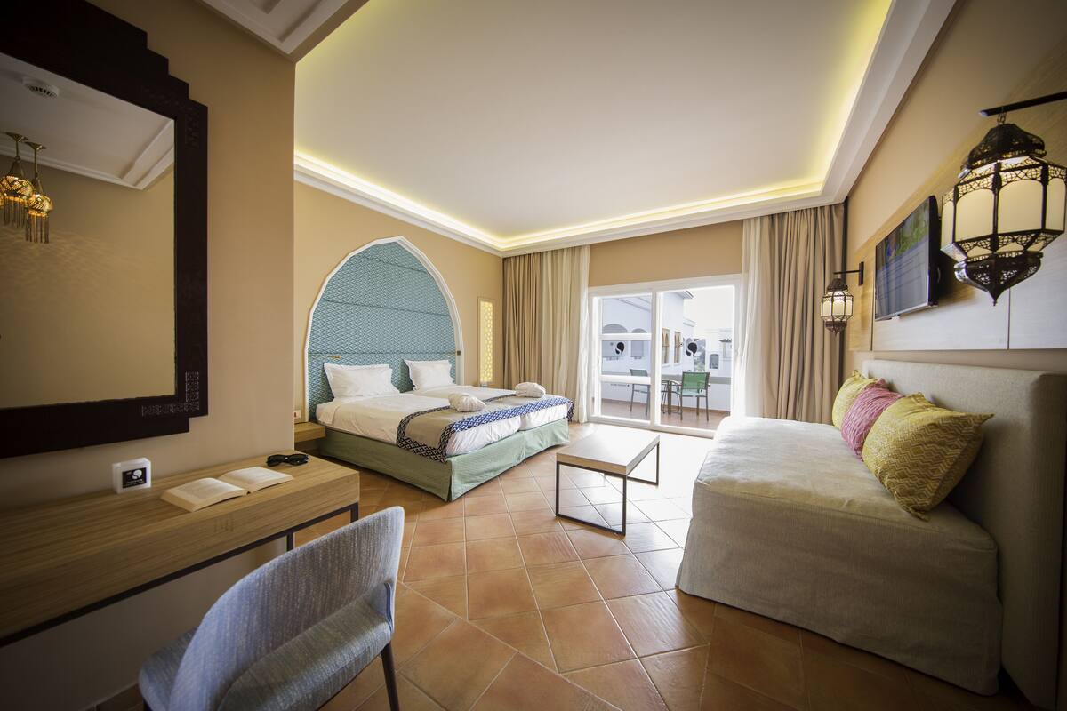 Quarto de hotel com cama, sofá, escrivaninha e cadeira.