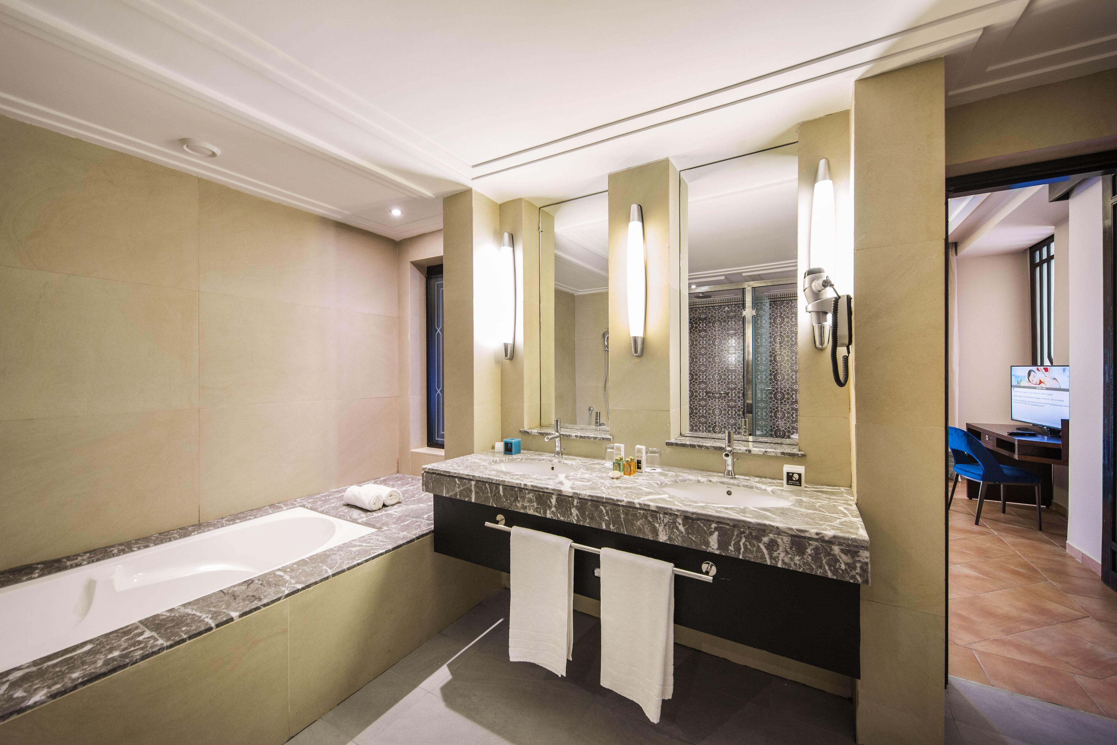 A modern bathroom with a large bathtub, a double sink vanity, and a large mirror.