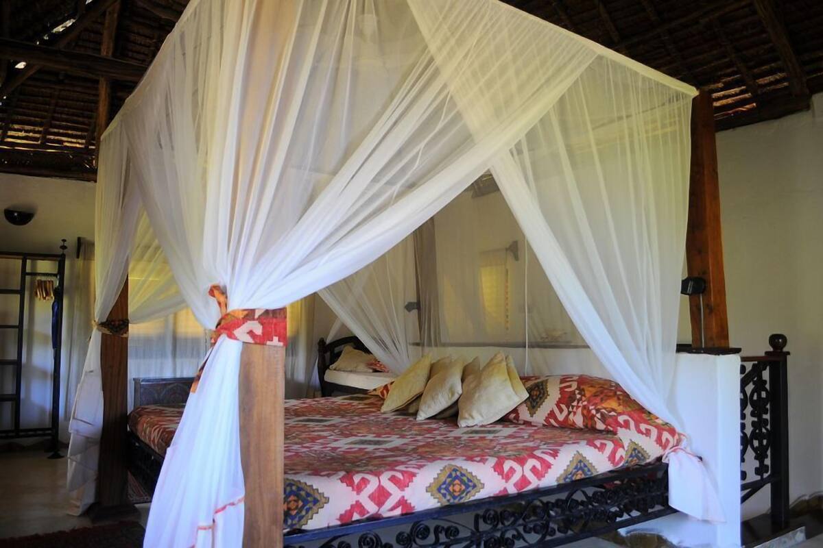 A bed with a canopy, a wooden headboard, and patterned bedding.