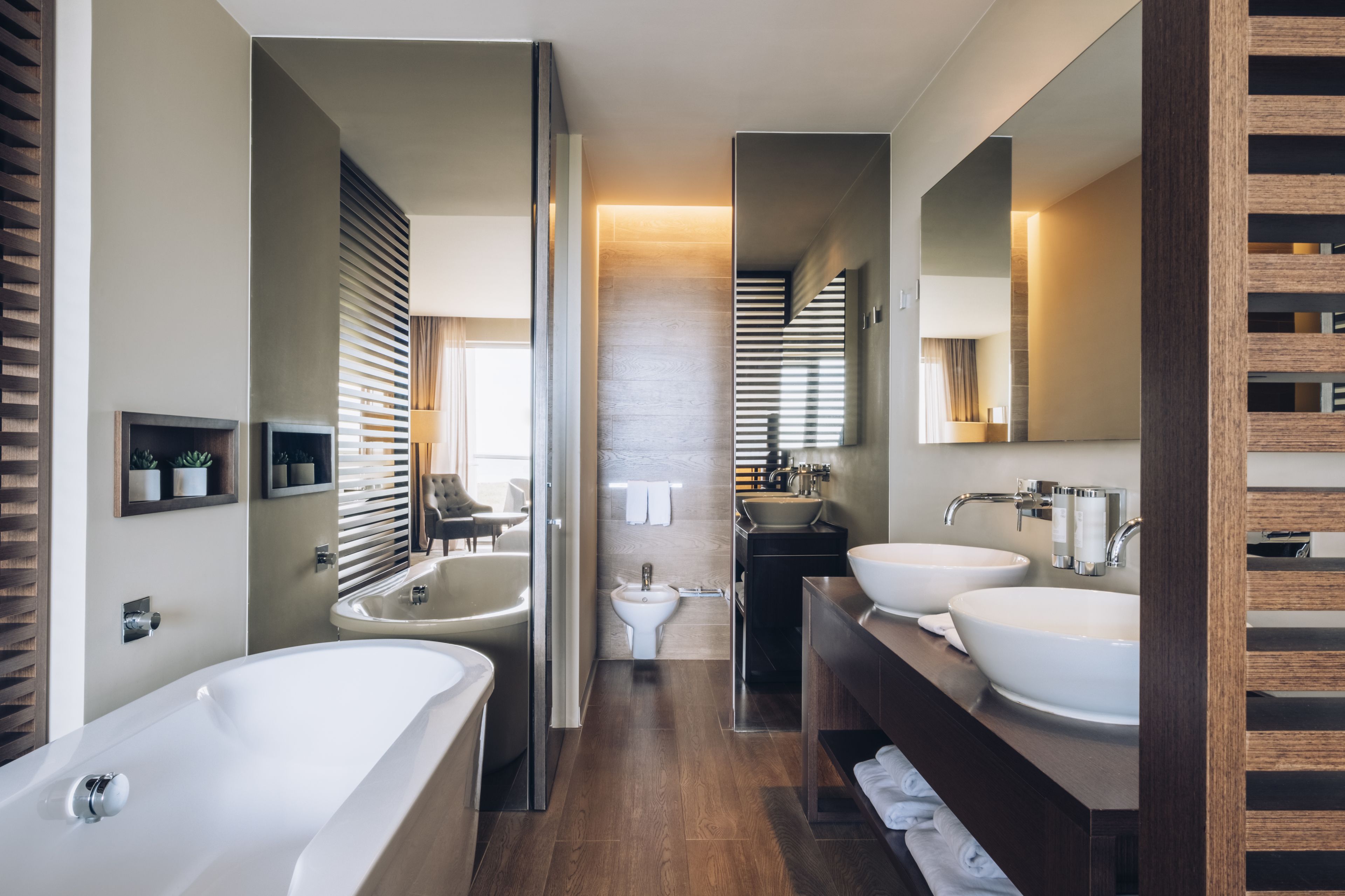 A modern bathroom with a freestanding bathtub, two sinks, and a vanity.