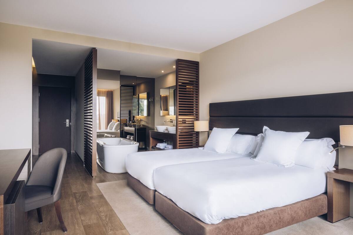 A modern hotel room with a large bed, a desk, and a bathroom area.