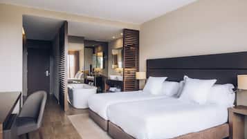 Ein Hotelzimmer mit einem großen Bett, einem Schreibtisch, einem Sessel sowie einem Badezimmer mit einer Badewanne und einem Spiegel.