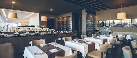 A modern restaurant with multiple dining tables, chairs, and a bar area.