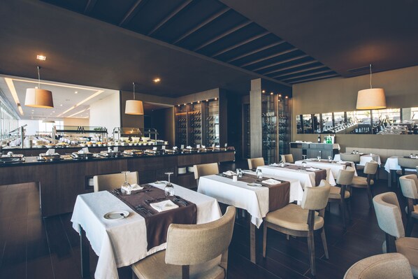 A modern restaurant with multiple dining tables, chairs, and a bar area. - Iberostar Selection Lagos Algarve (Lagos)