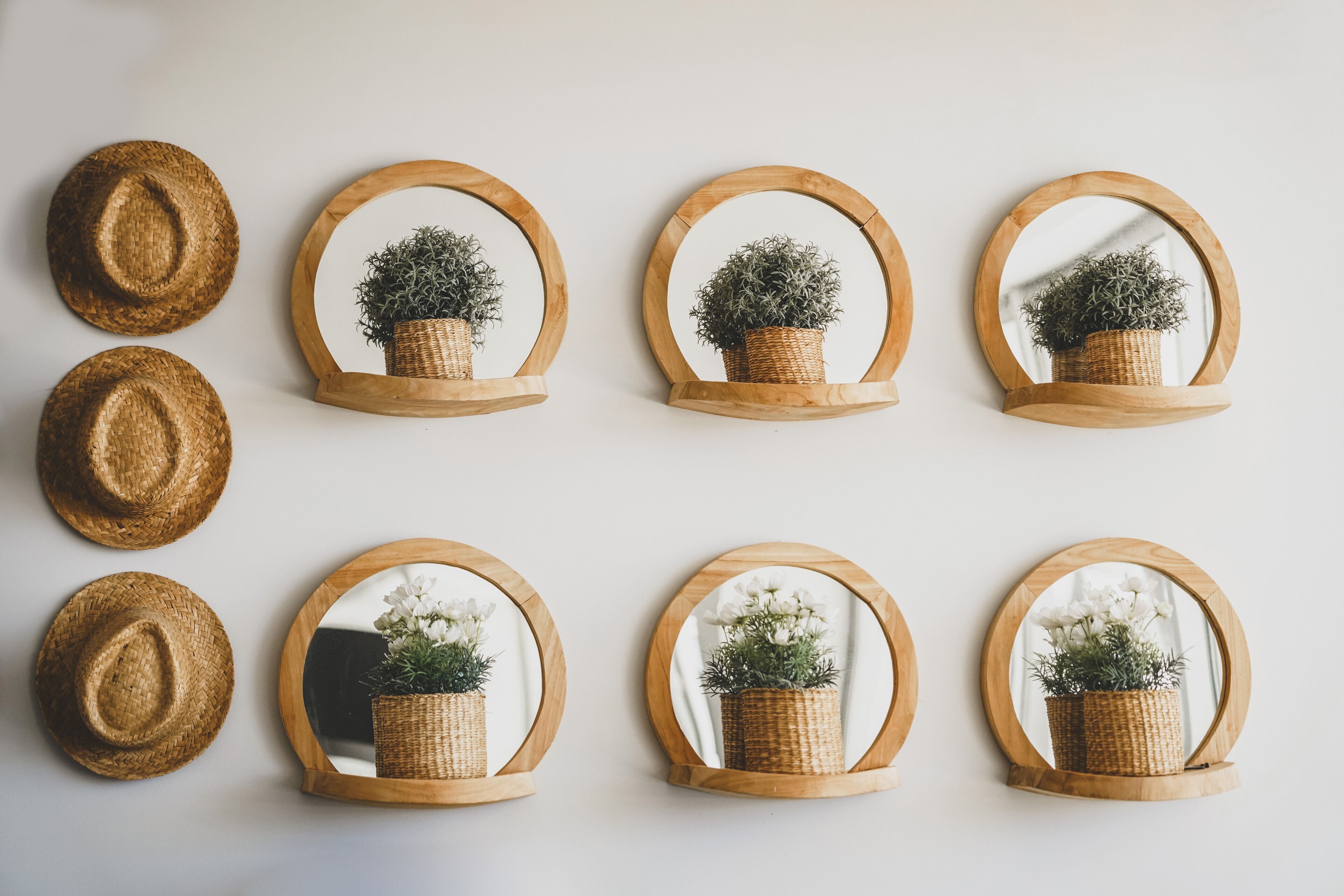 A wall with eight wooden-framed mirrors, each with a wicker basket containing plants.