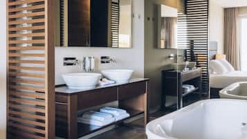 Un baño moderno con dos lavamanos, una bañera grande y estantes de madera con listones.