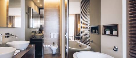 Un bagno moderno con due ampi lavabi, una vasca freestanding e un bidet.