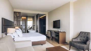 Ein modernes Hotelzimmer mit Bett, Schreibtisch, Stuhl, Fernseher und einer Couch.