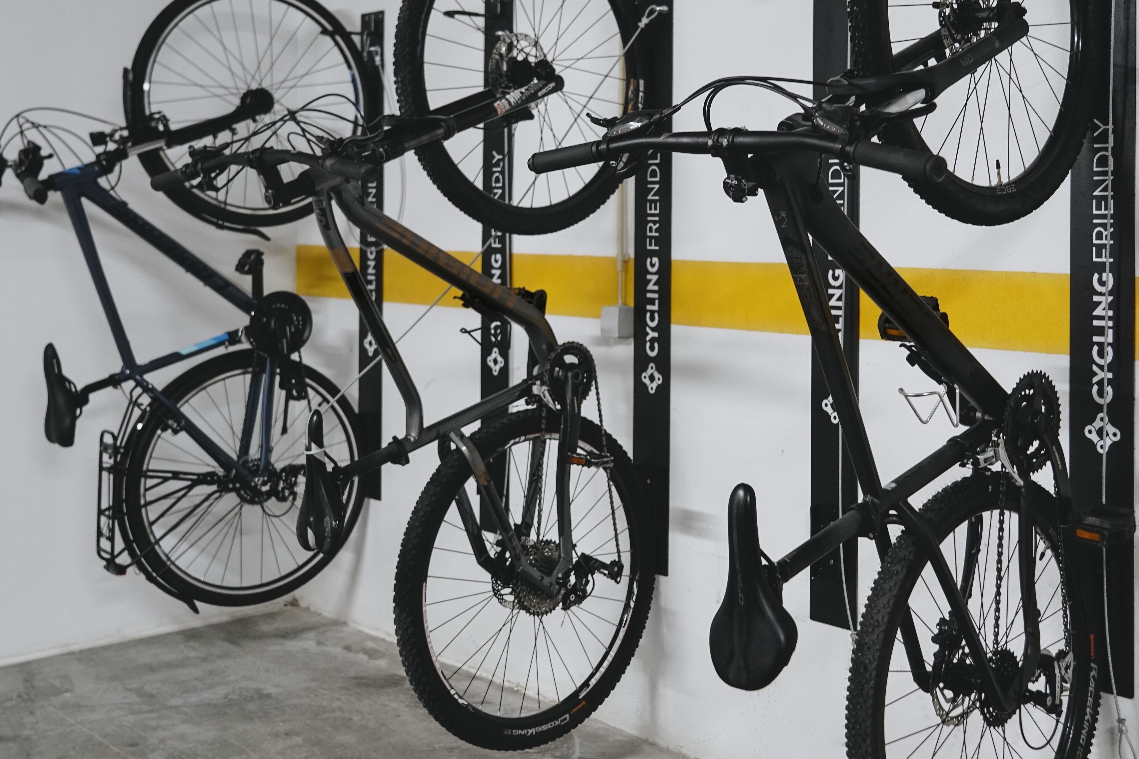 Un aparcaciclos con varias bicicletas, una franja amarilla en la pared y un candado para bicicleta.