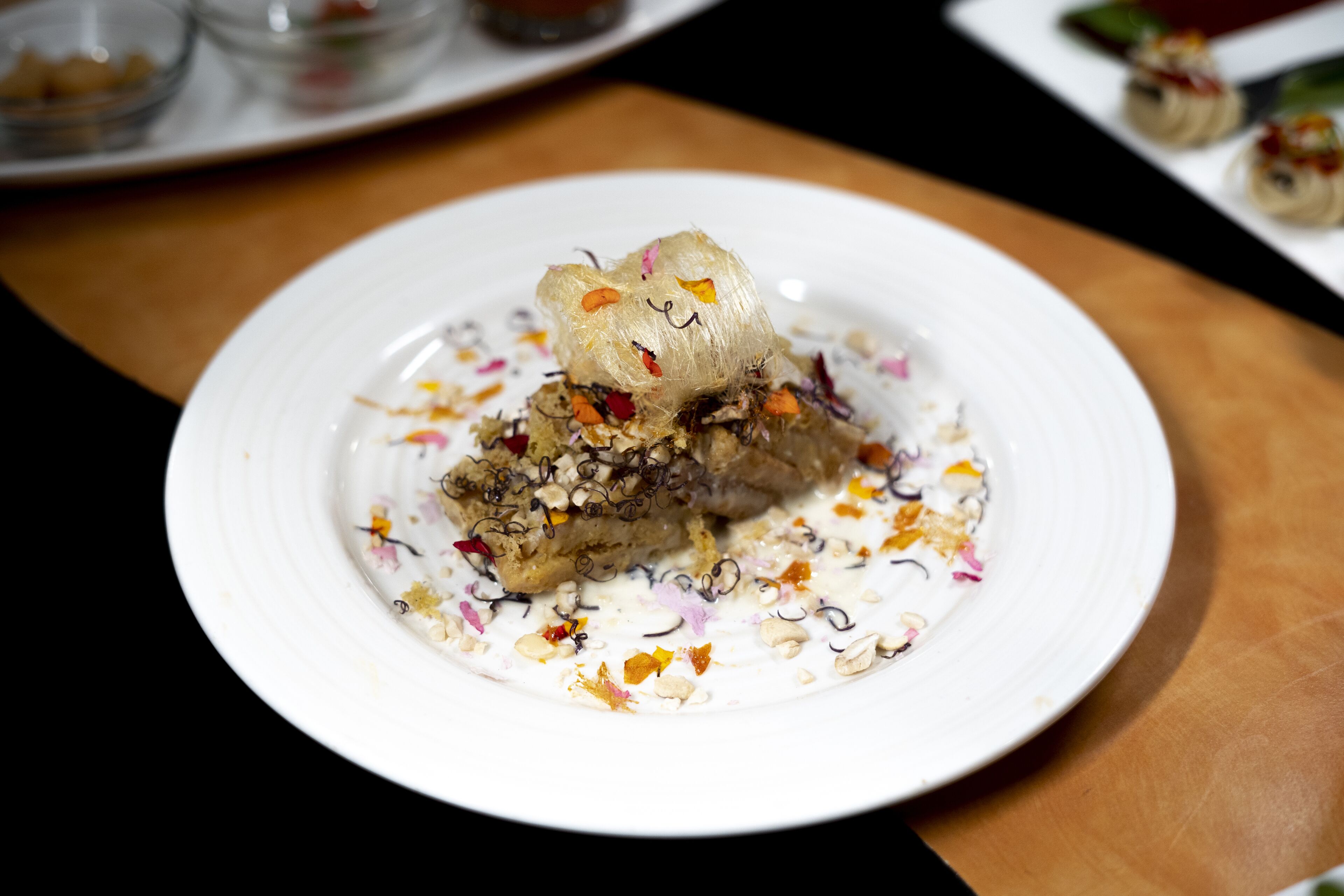 A dessert on a white plate with colorful toppings and a decorative element on top.