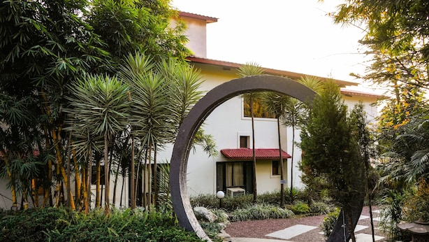 Un elemento architettonico circolare in un giardino, con un edificio sullo sfondo.