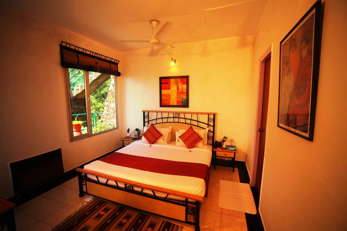 A bedroom with a bed, a nightstand, a window with a view of greenery, and a ceiling fan.