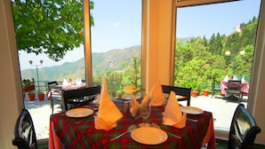 A table set for dining with a view of the mountains. - Country Inn (Dehradun)
