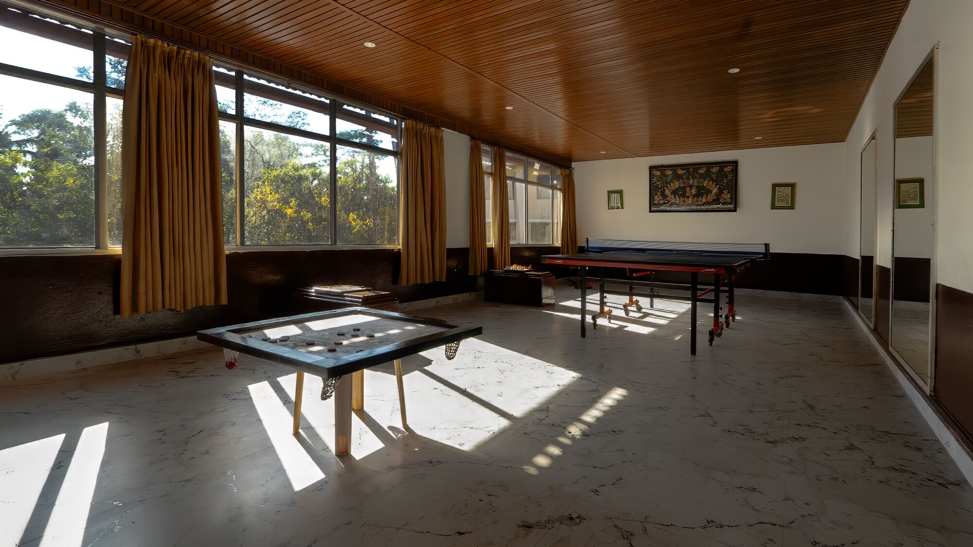 Um quarto com mesa de pebolim, mesa de sinuca e uma mesa de pebolim com a rede.