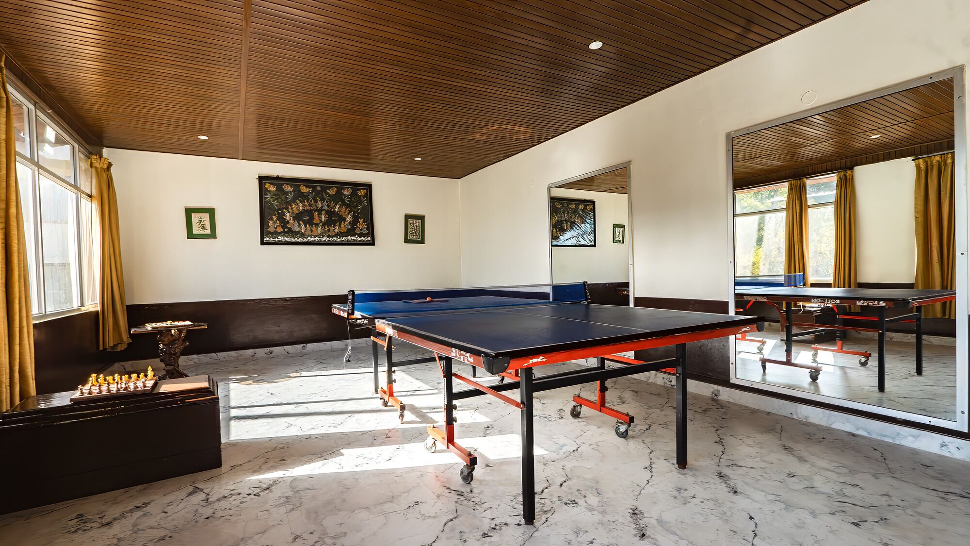 Una habitación con mesa de ping pong, tablero de ajedrez y obras de arte en las paredes.