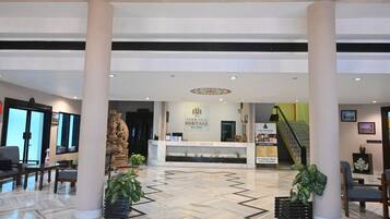 A hotel lobby with a reception desk, a statue, and a staircase.