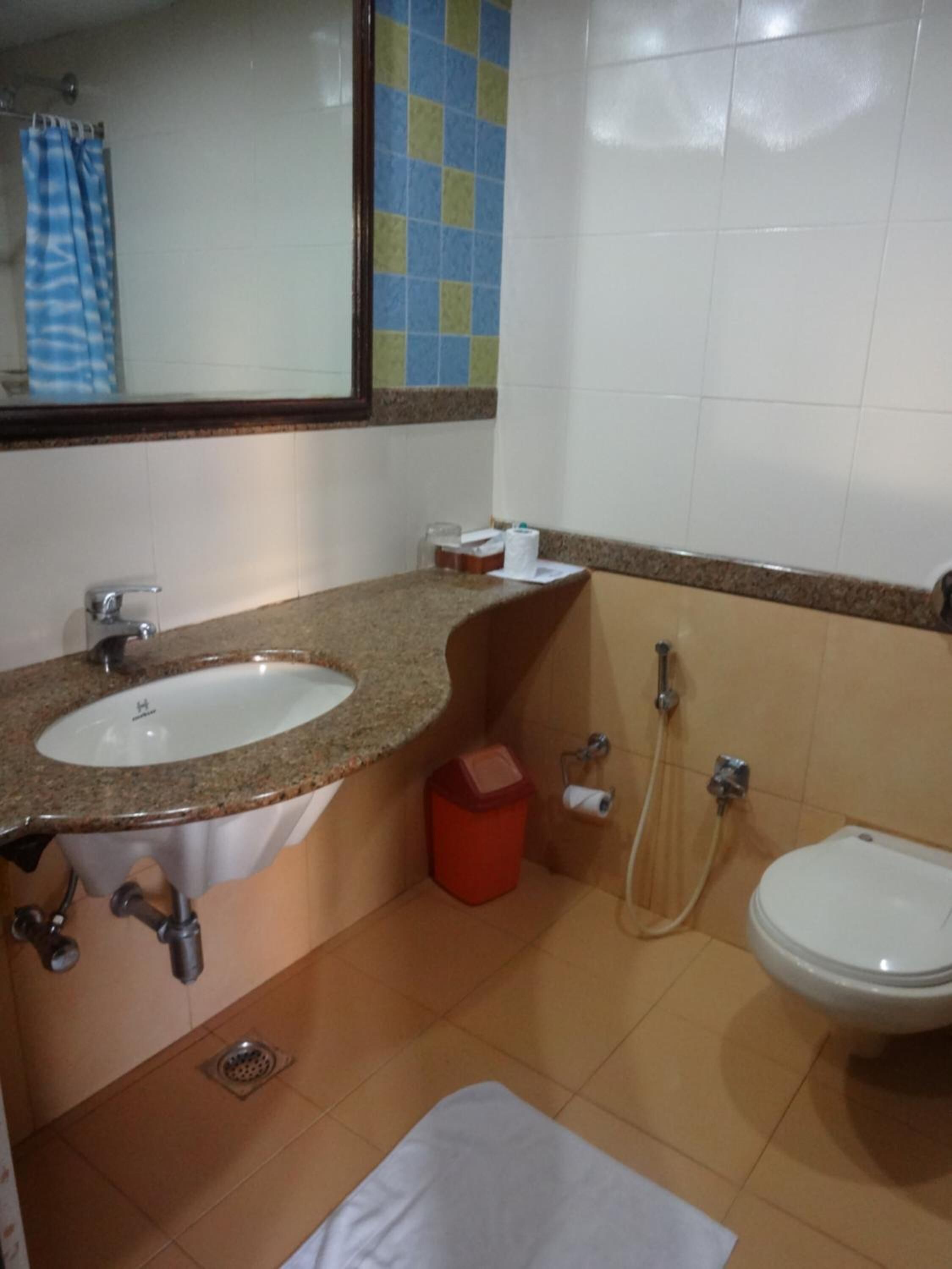 A bathroom with a sink, toilet, shower, and a mirror.