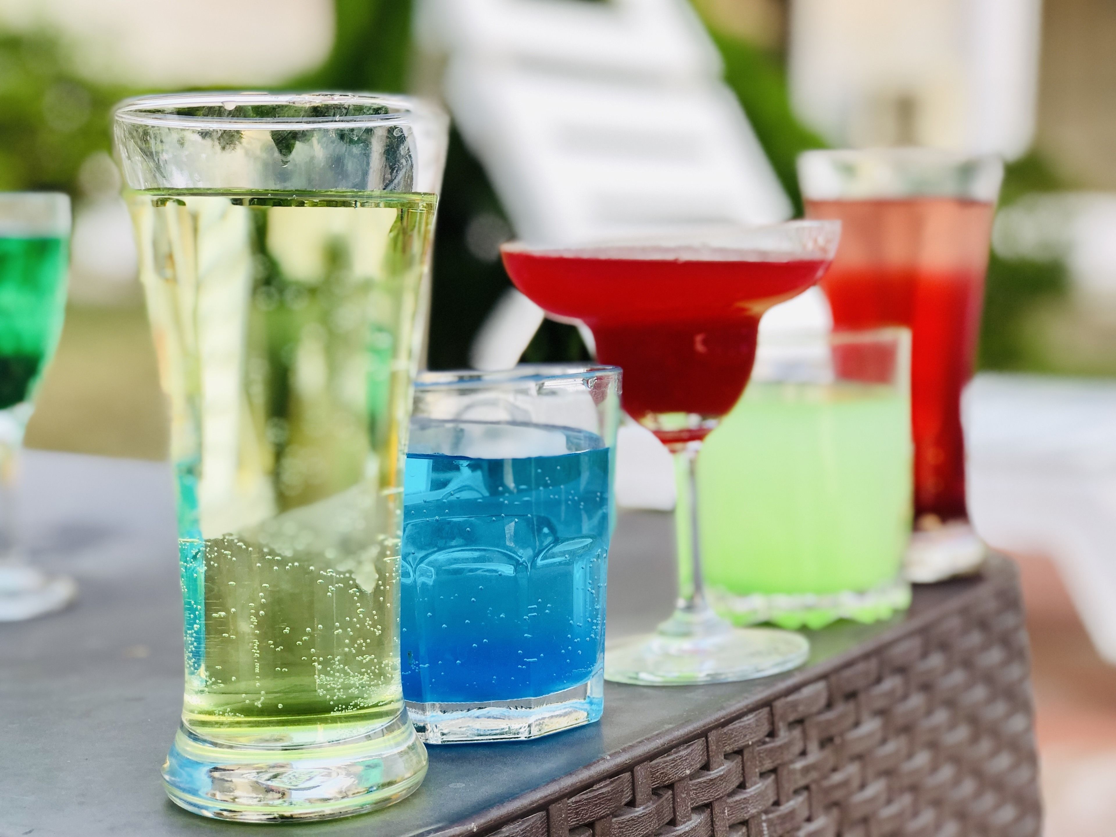 Variedad de bebidas coloridas en diferentes vasos sobre una mesa.