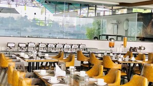 A restaurant with multiple tables and chairs, equipped with coffee machines and a tea dispenser.