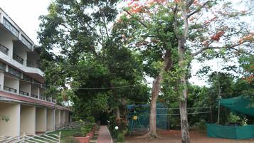 Un edificio de varios pisos, un sendero que conduce a un área verde con árboles y un columpio.