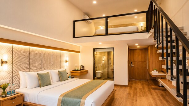 A modern hotel room with a large bed, a wooden floor, a staircase, and a balcony.