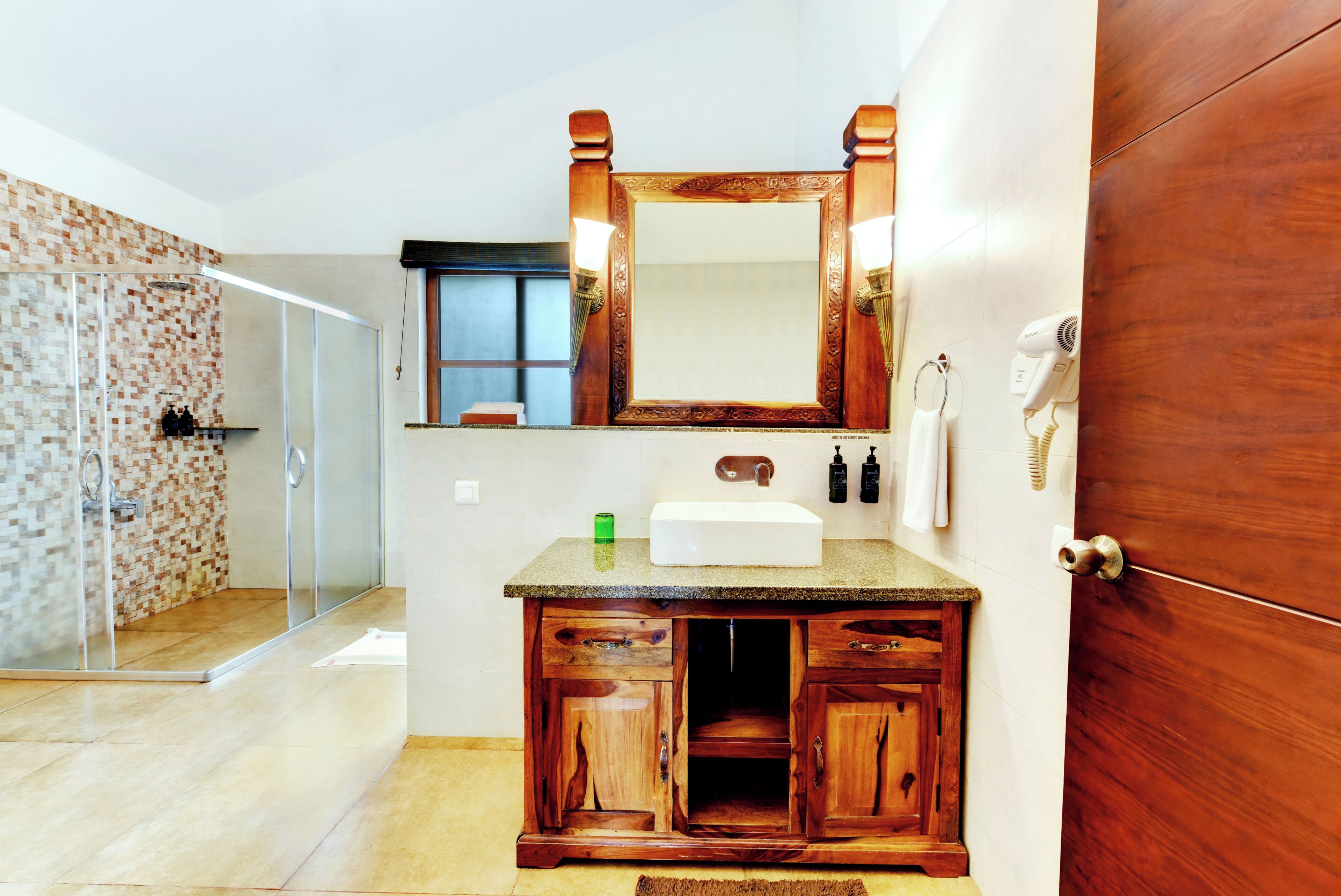 A bathroom with a wooden vanity, a mirror, a sink, and a hairdryer.