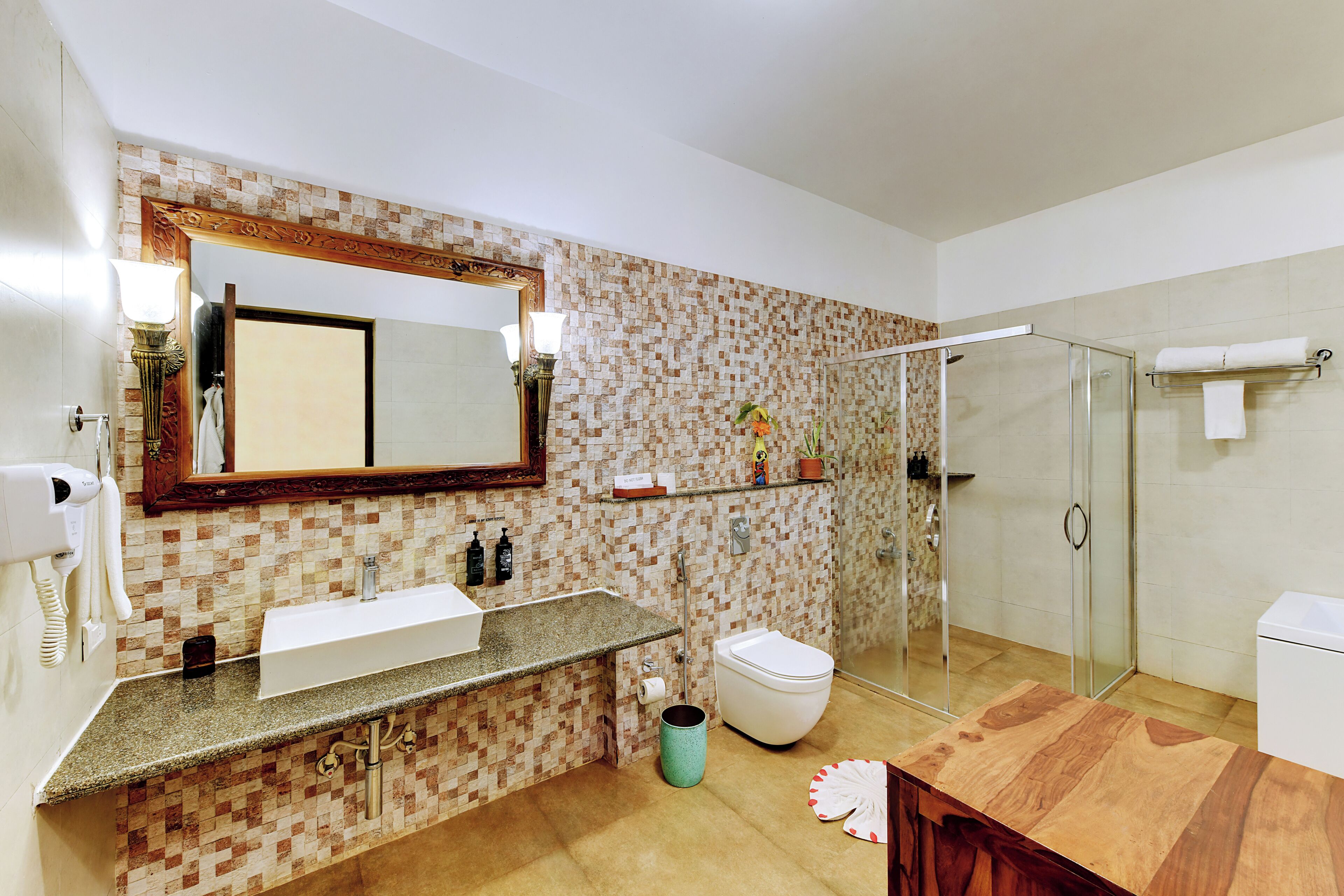A bathroom with a tiled backsplash, a large mirror, a sink, a toilet, a shower, and a wooden vanity.