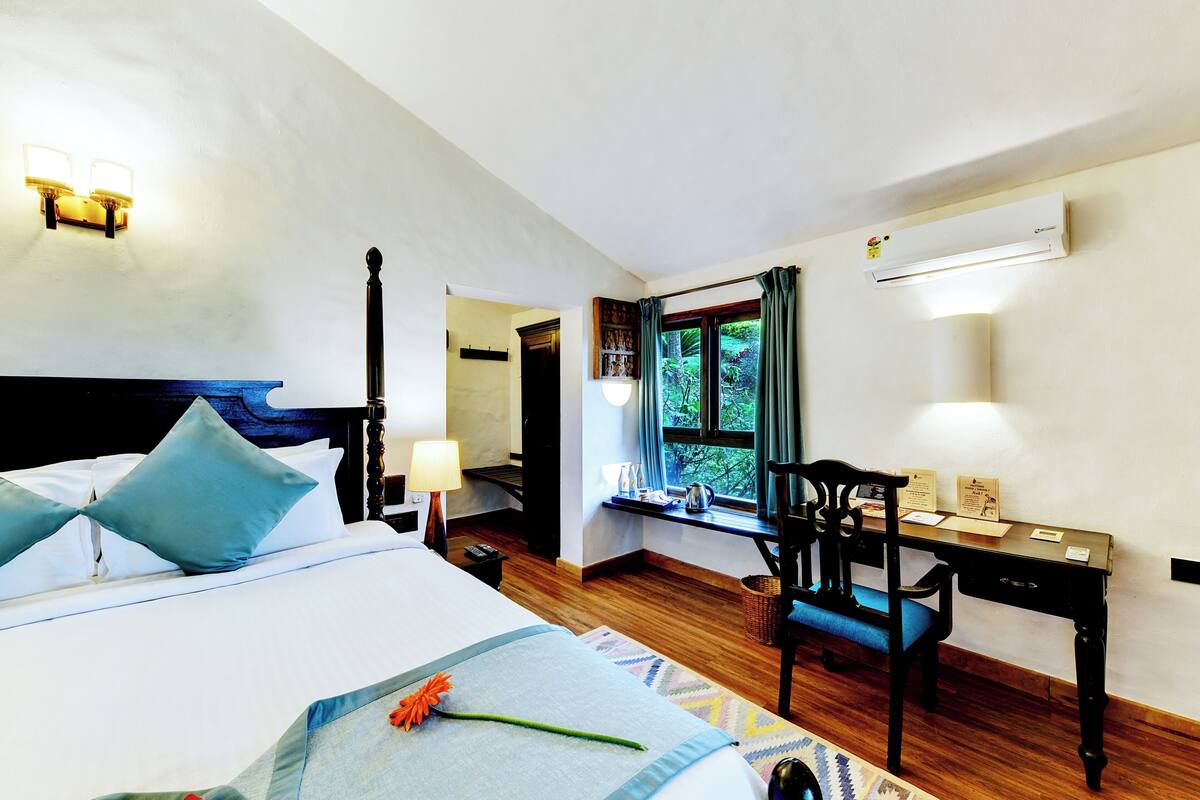 A hotel room with a bed, desk, and window with curtains.