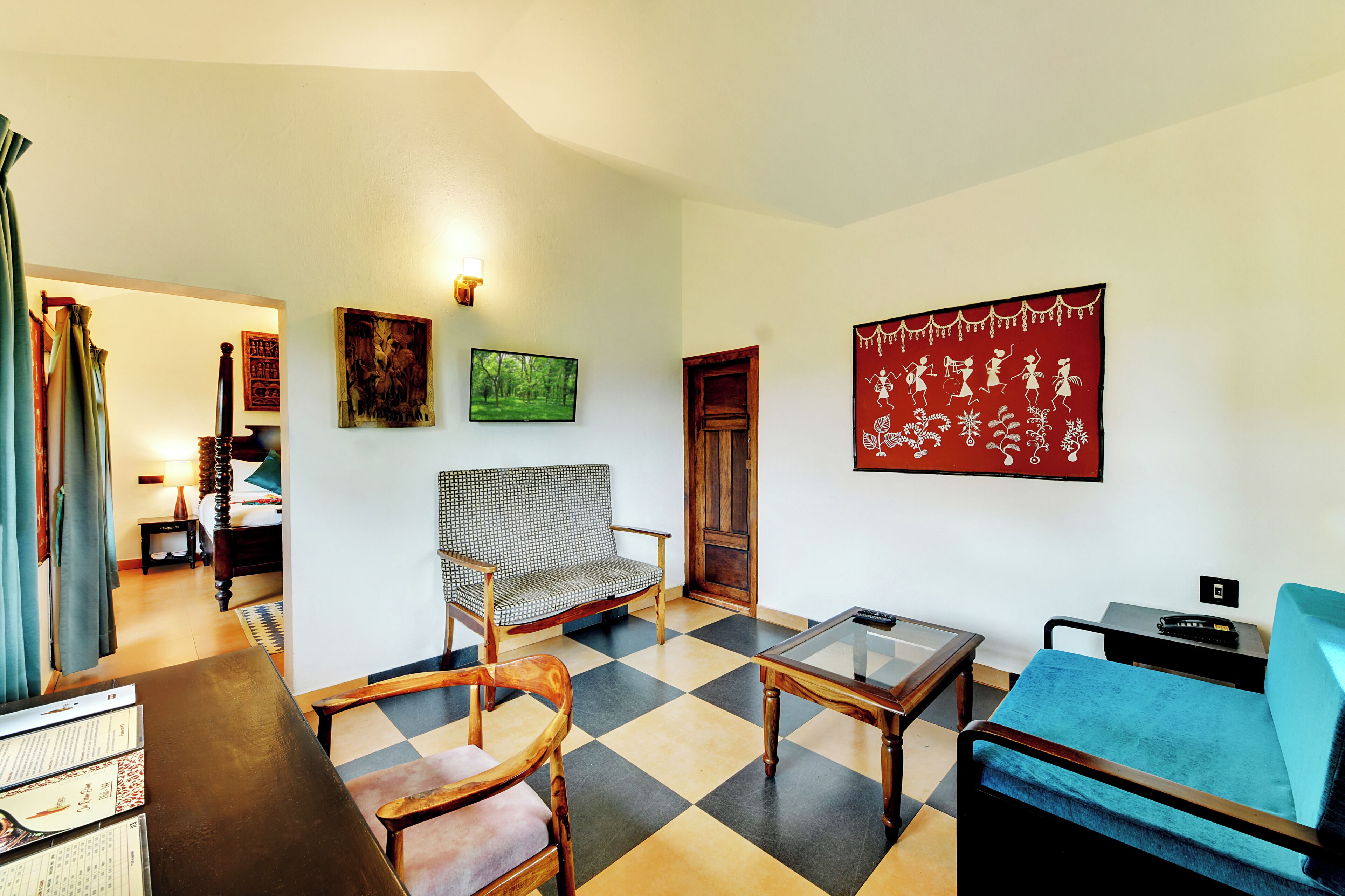 A living room with a checkered floor, a sofa, a chair, a television, and artwork on the walls.