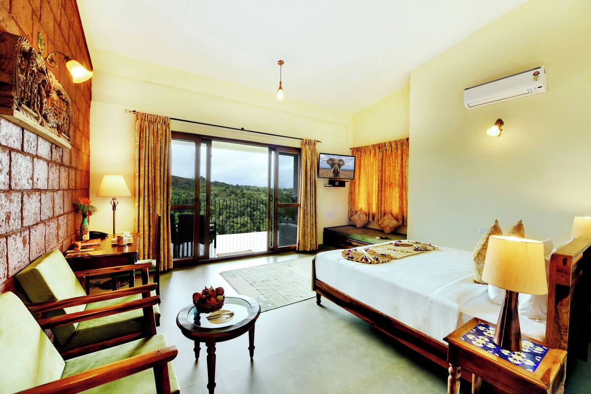 A hotel room with a bed, a desk, a chair, a TV, and a view of the outdoors.
