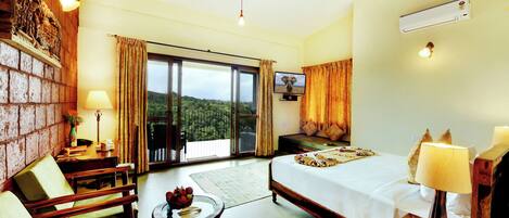 Habitación de hotel con cama, escritorio, silla, televisor y vistas al exterior.