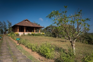 A bungalow with a tiled roof, surrounded by a well-maintained lawn and a variety of shrubs and trees. - Indo Asia Heritage, Coorg (Madikeri)