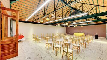 Un salón amplio con techo alto, asientos distribuidos y una zona de escenario.
