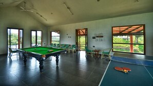 A spacious indoor area with a pool table, green chairs, and a ping pong table. - Indo Asia Heritage, Coorg (Madikeri)
